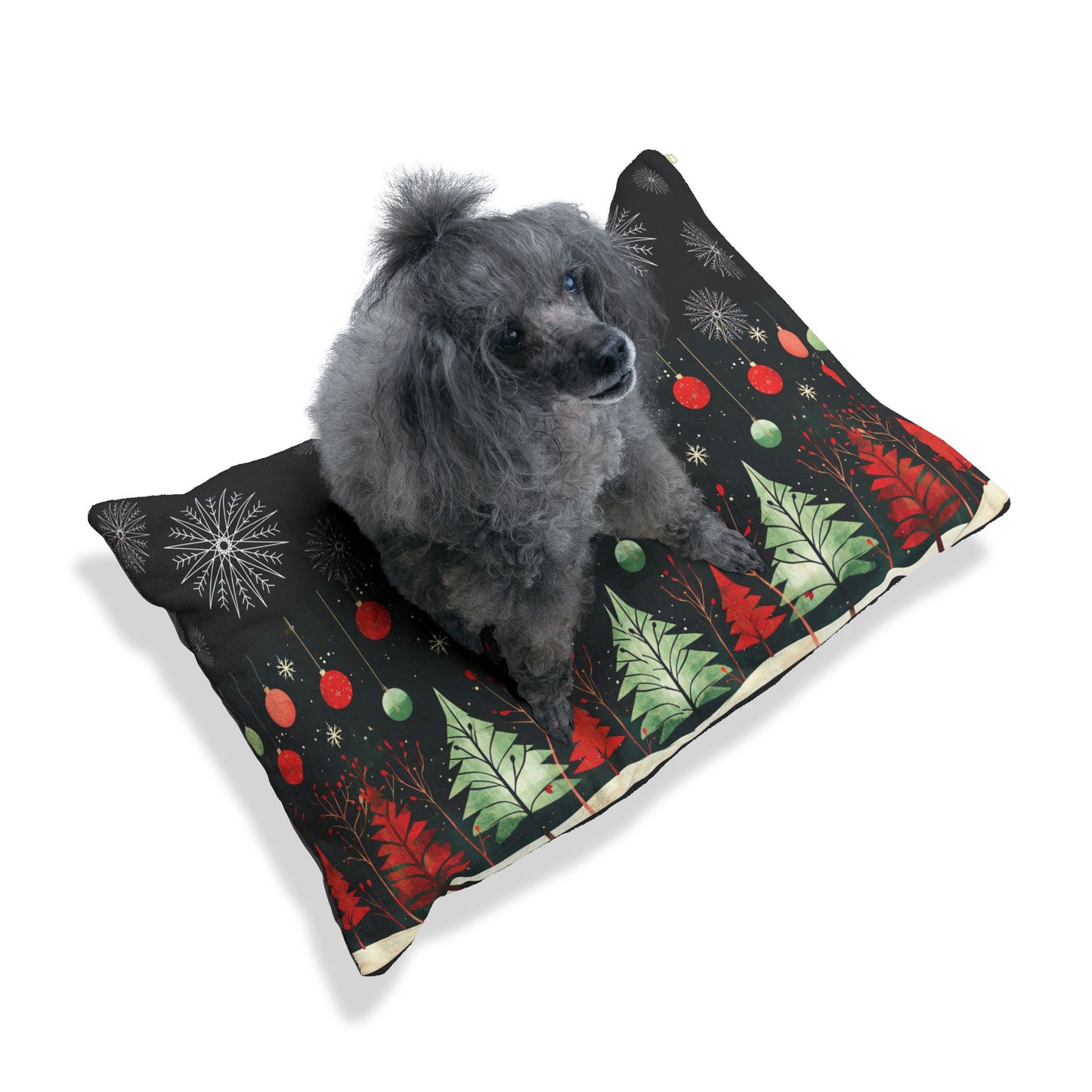 A small gray dog sits on a rectangular pet bed with a black background and a festive Christmas tree pattern in red, green, and white, photographed on a clean white background.