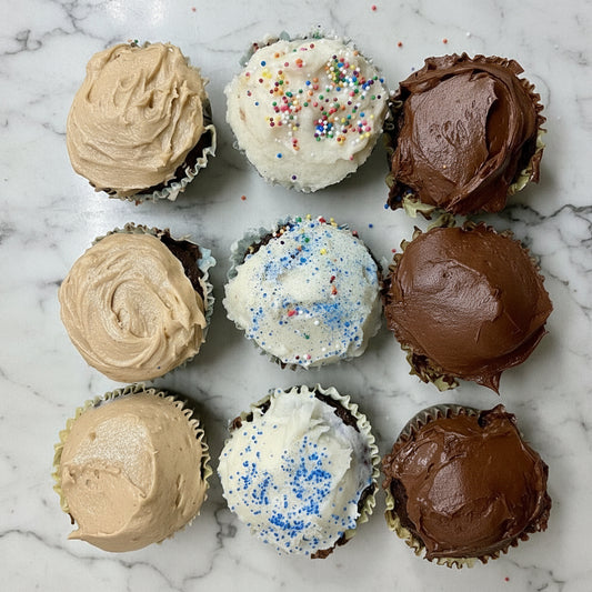 Assorted cupcakes with different frosting flavors on a baking tray.