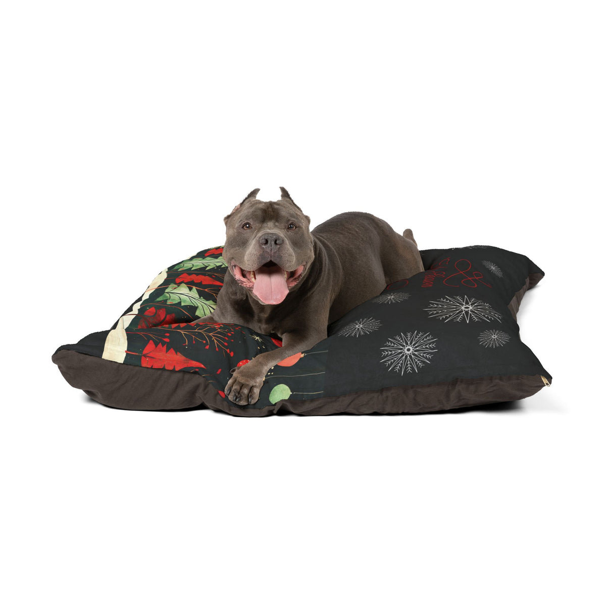 A gray pitbull-type dog lies on a rectangular dog bed with a dark patterned top and a red, green, and cream patterned side, photographed on a clean white background.
