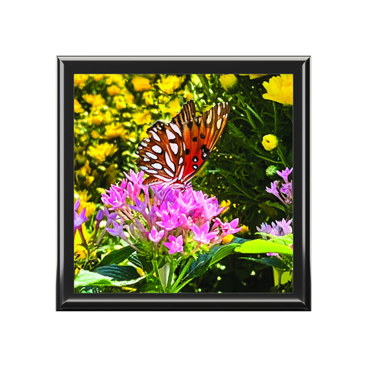 Framed artwork of a butterfly on pink flowers with yellow flowers in the background