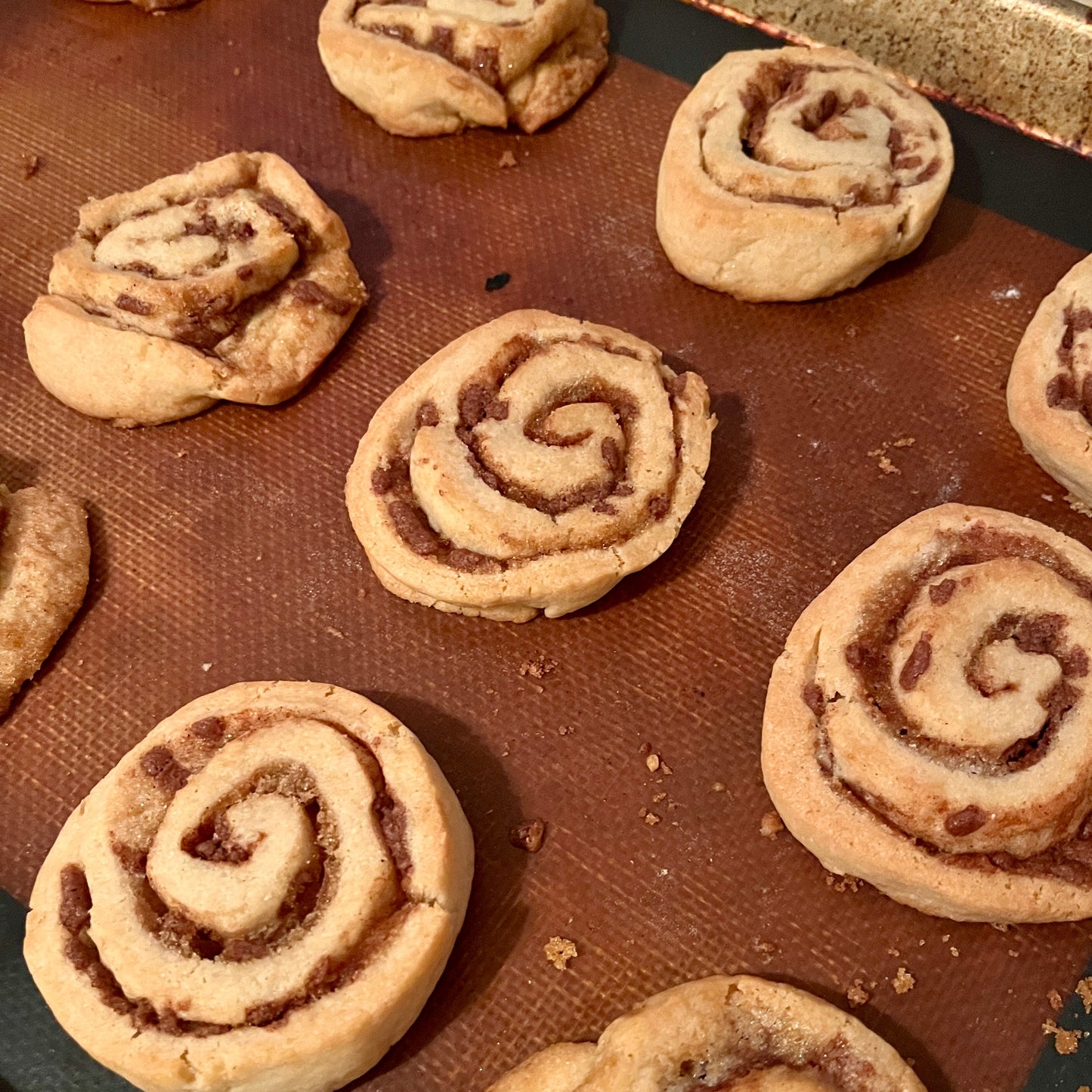 Cinnamon rolls on a baking sheet with a silicone mat
