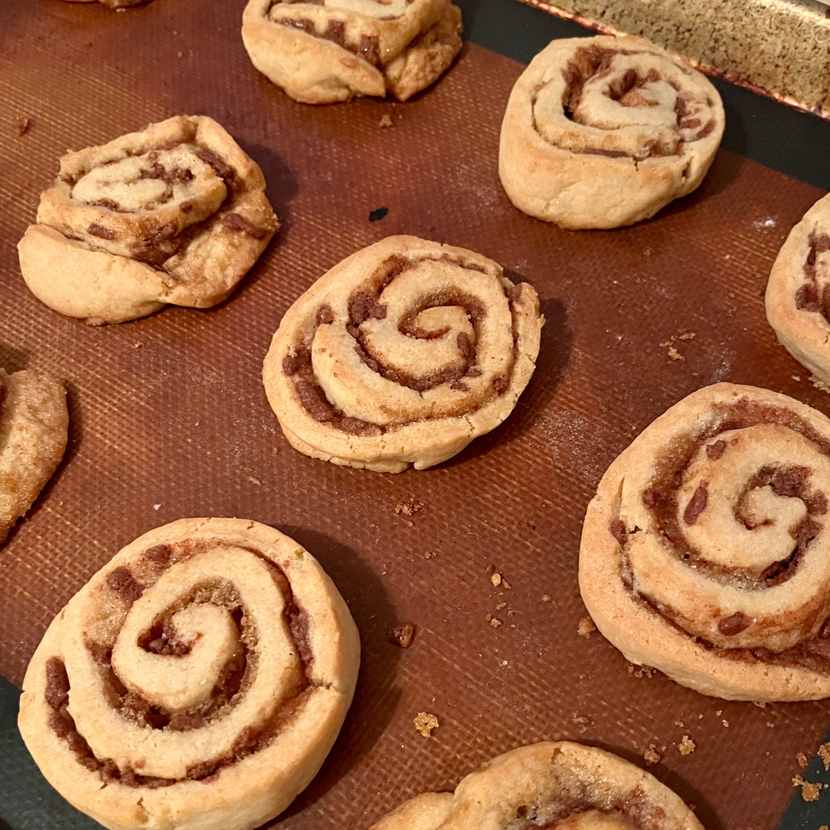 Cinnamon rolls on a baking sheet with a silicone mat