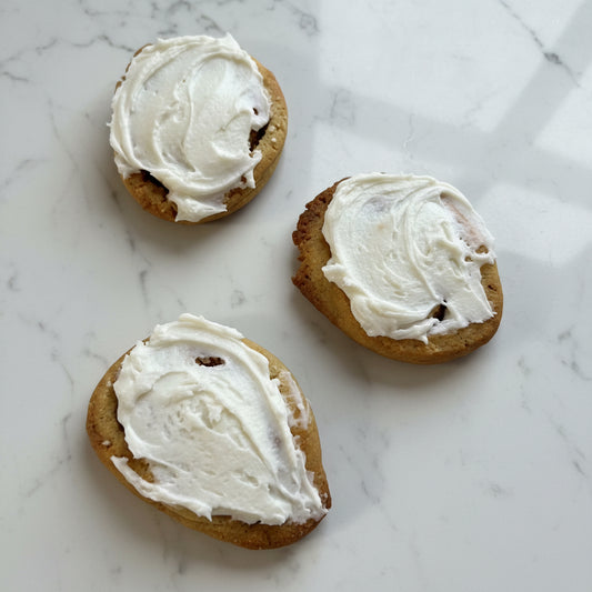 Three cookies with white frosting on a cooling rack.