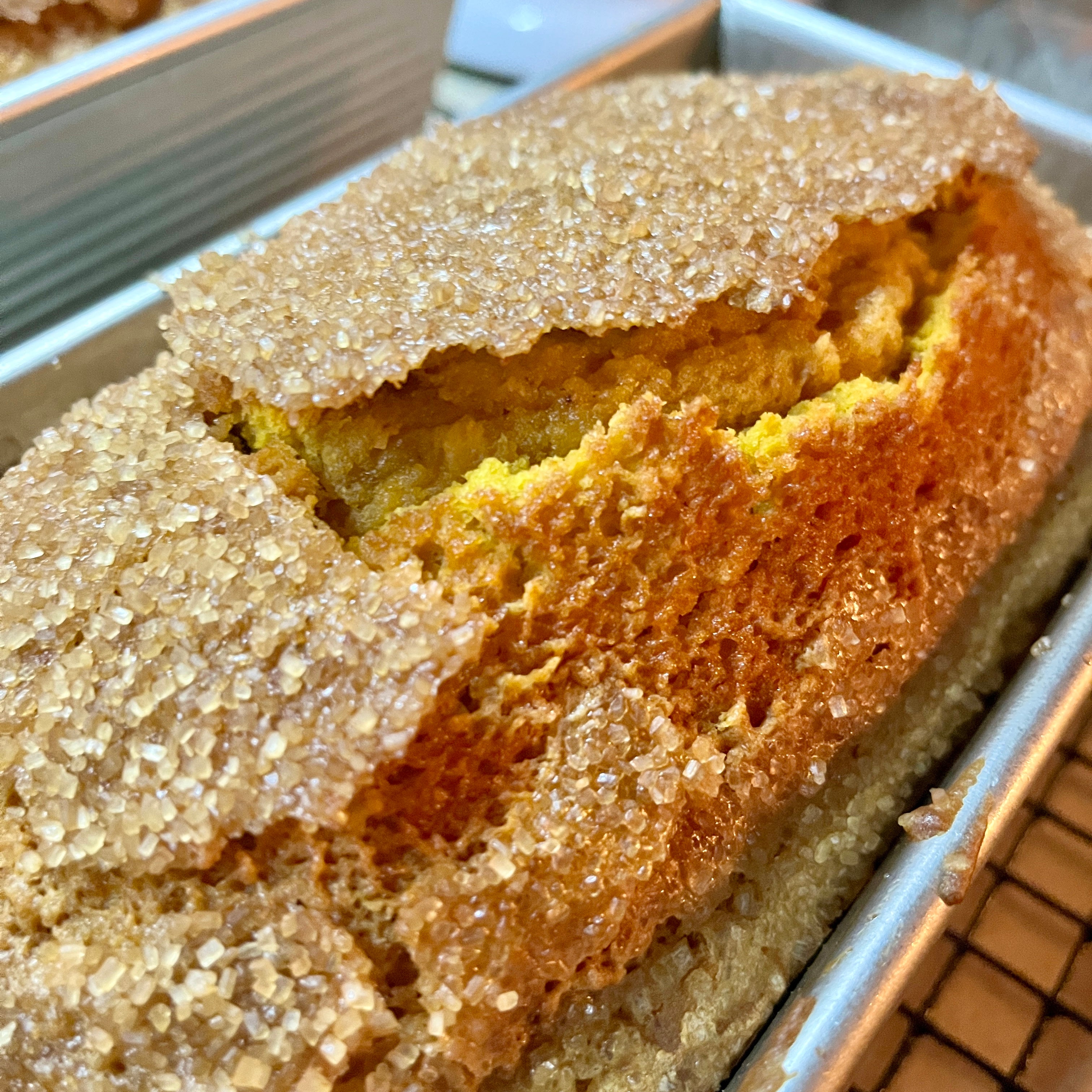 Close-up of a loaf of bread with a sugary crust on a cooling rack.