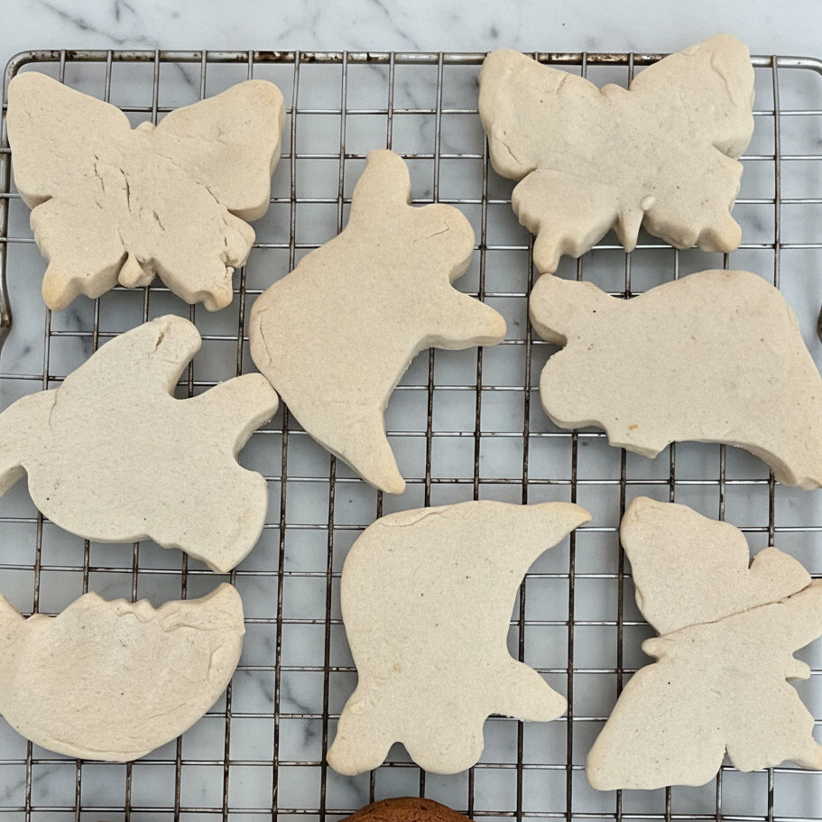 Baking tray with butterfly-shaped cookies and chocolate cookies on a cooling rack.