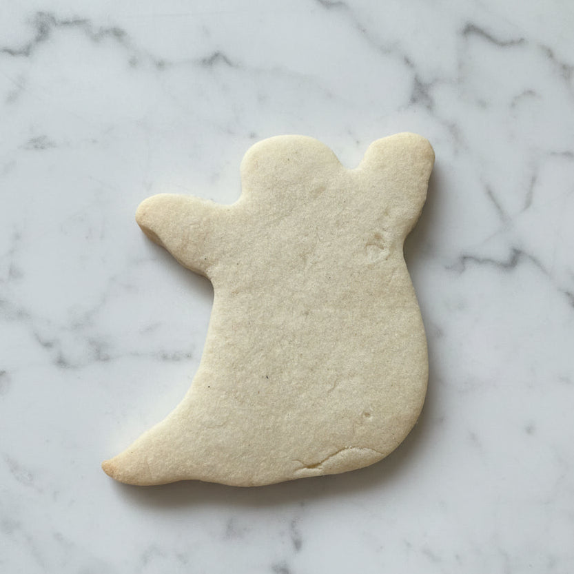 ghost shaped sugar cookie on white marble