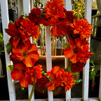 Decorative wreath with orange and red flowers on a white wooden door.