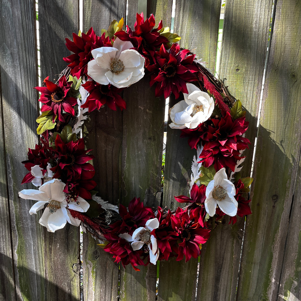 Floral wreath with red and white flowers on a wooden fence
