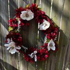 Floral wreath with red and white flowers on a wooden fence