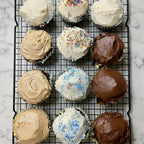 Assorted cupcakes with different frosting flavors on a baking tray.