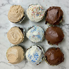 Assorted cupcakes with different frosting flavors on a baking tray.