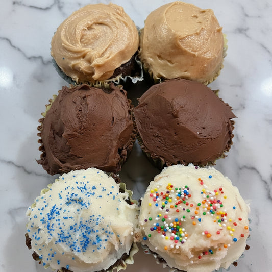 Assorted cupcakes with different flavors and toppings in a foil tray.