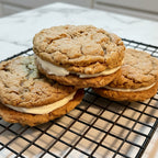 Three cookie sandwiches with cream filling on a cooling rack.