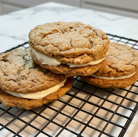 Three cookie sandwiches with cream filling on a cooling rack.