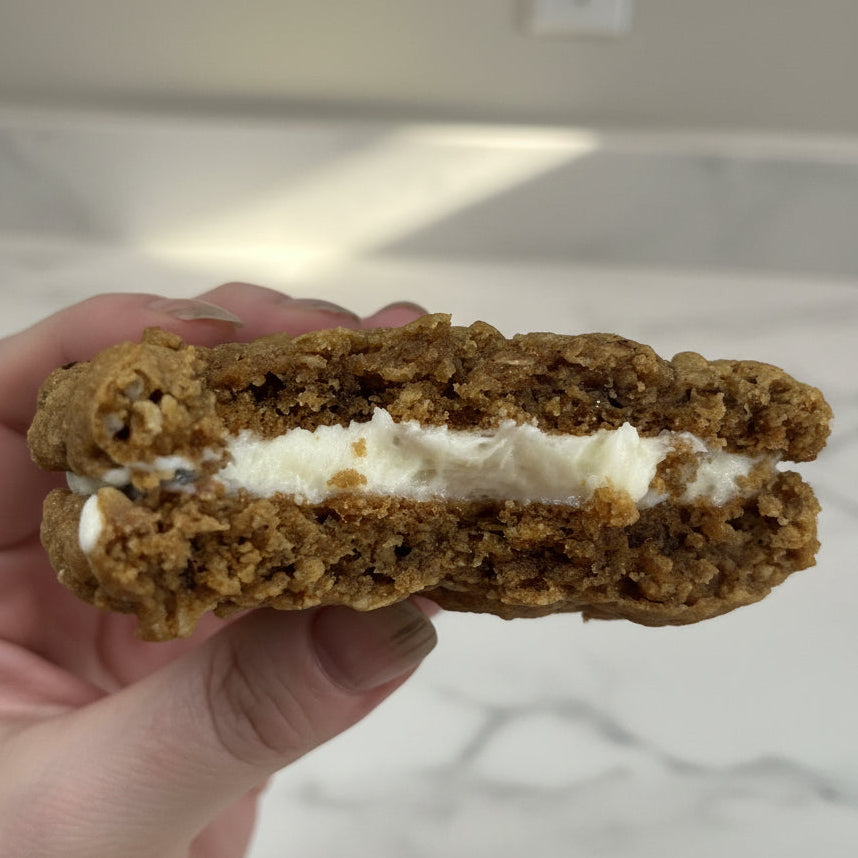 Close-up of a cookie with cream filling held by a hand against a blurred background